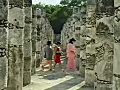 RoyaltyFreeStockVideoSDFootageZoomIntoColumnsofMayanTempleasTouristsPassbyatChichenItzainMexico